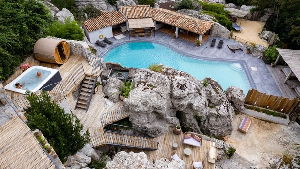 Ein Poolbereich mit Whirlpool, Holzterrasse und Felsformationen.