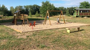 Ein Spielplatz mit Schaukel, Rutsche und einer kleinen Holzkonstruktion.