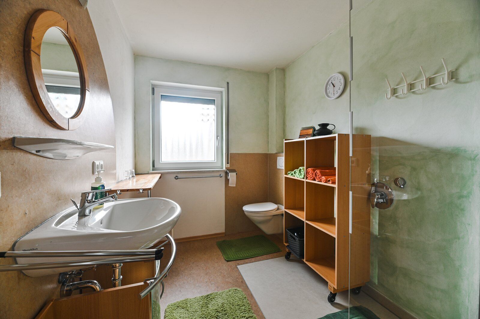 Une petite salle de bain comprenant un lavabo, un miroir, des toilettes et une étagère avec des serviettes.