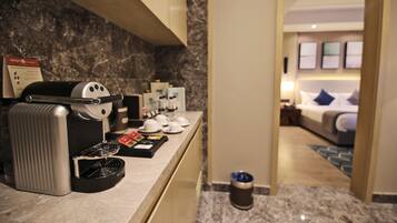 A hotel room with a marble countertop, a coffee machine, and a bed with a blue pillow.