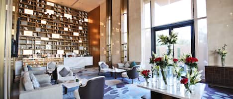 A modern lobby with a large bookshelf, seating area, and a view of the outdoors.