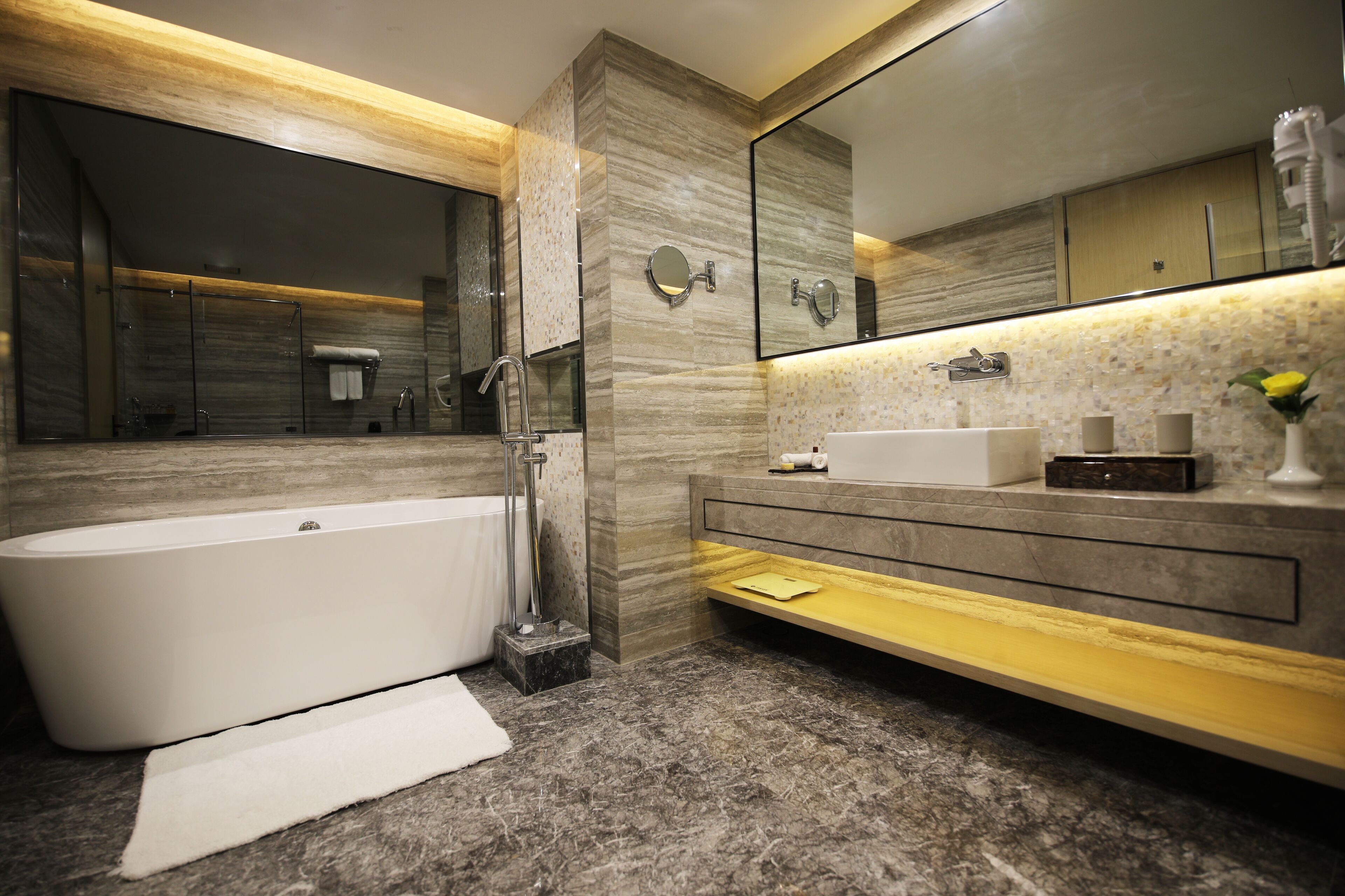A modern bathroom with a freestanding bathtub, a large mirror, and a vanity with a sink and towel rack.