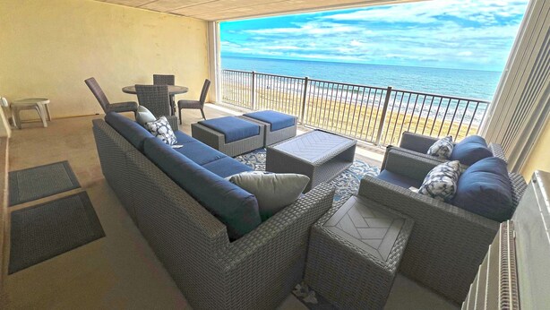 A balcony with wicker furniture, a small table, and a view of the ocean. - Newly renovated 2 bedroom, 2 bath condo with beautiful views of the ocean! (Ocean City)