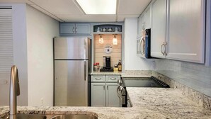 Una cocina con refrigerador de acero inoxidable, estación de café integrada y encimera de granito.