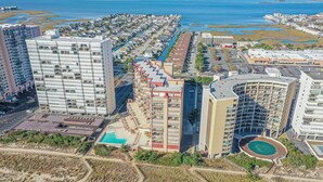 Un hotel de gran altura con varios pisos, una piscina y una zona de playa.