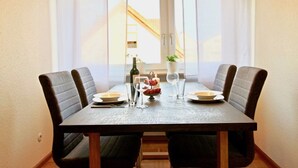 A dining table with four chairs, a bottle, glasses, and a small plant.