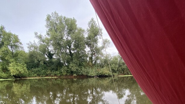 A man relaxing in a hot tub on a wooden deck with a bench and a red curtain. - Toue cabanée spa (Chassenard)