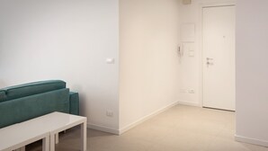 Una habitación moderna y minimalista con un sofá color turquesa, una mesa blanca y una puerta blanca.