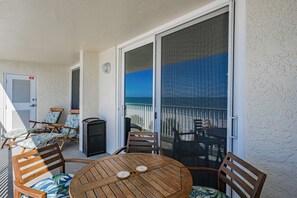 Uma varanda com uma mesa de madeira redonda, cadeiras e uma porta de vidro deslizante que dá para uma varanda com vista.