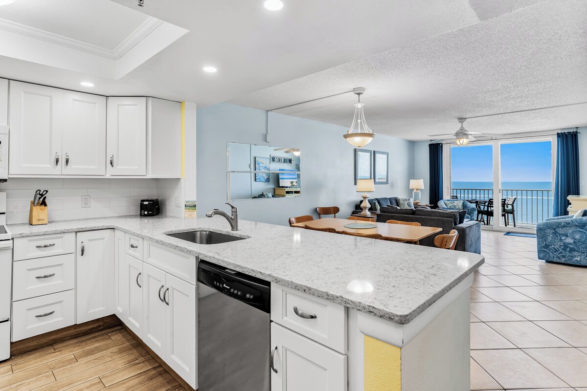 A modern kitchen with white cabinets, a dishwasher, and a dining area with a table and chairs.