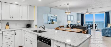 A modern kitchen with white cabinets, a dishwasher, and a dining area with a table and chairs.