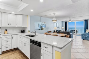 A modern kitchen with white cabinets, a dishwasher, and a dining area with a table and chairs.
