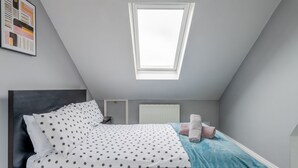 Ein Schlafzimmer mit Bett, Dachfenster, Heizkörper und einem Handtuch auf dem Bett.