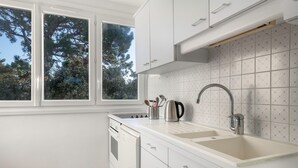 Cocina moderna con muebles blancos, un lavamanos doble y una ventana con vistas a árboles.