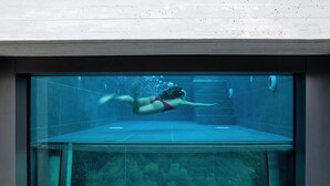 An underwater view of a swimming pool with a person swimming. - Neoma  (Athens)