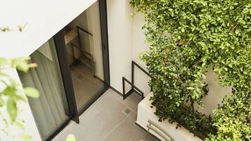 A modern outdoor patio with a table and chairs, surrounded by lush greenery.