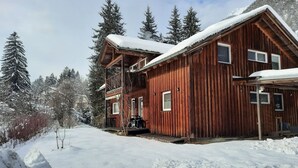 A wooden cabin with a balcony, surrounded by snow-covered trees and a clear sky. - Poludnig, cozy 5 P apartment (Presseggersee)