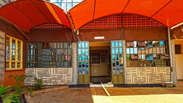 A building with a covered entrance, large windows, and a sign that reads "RILIPICIN".