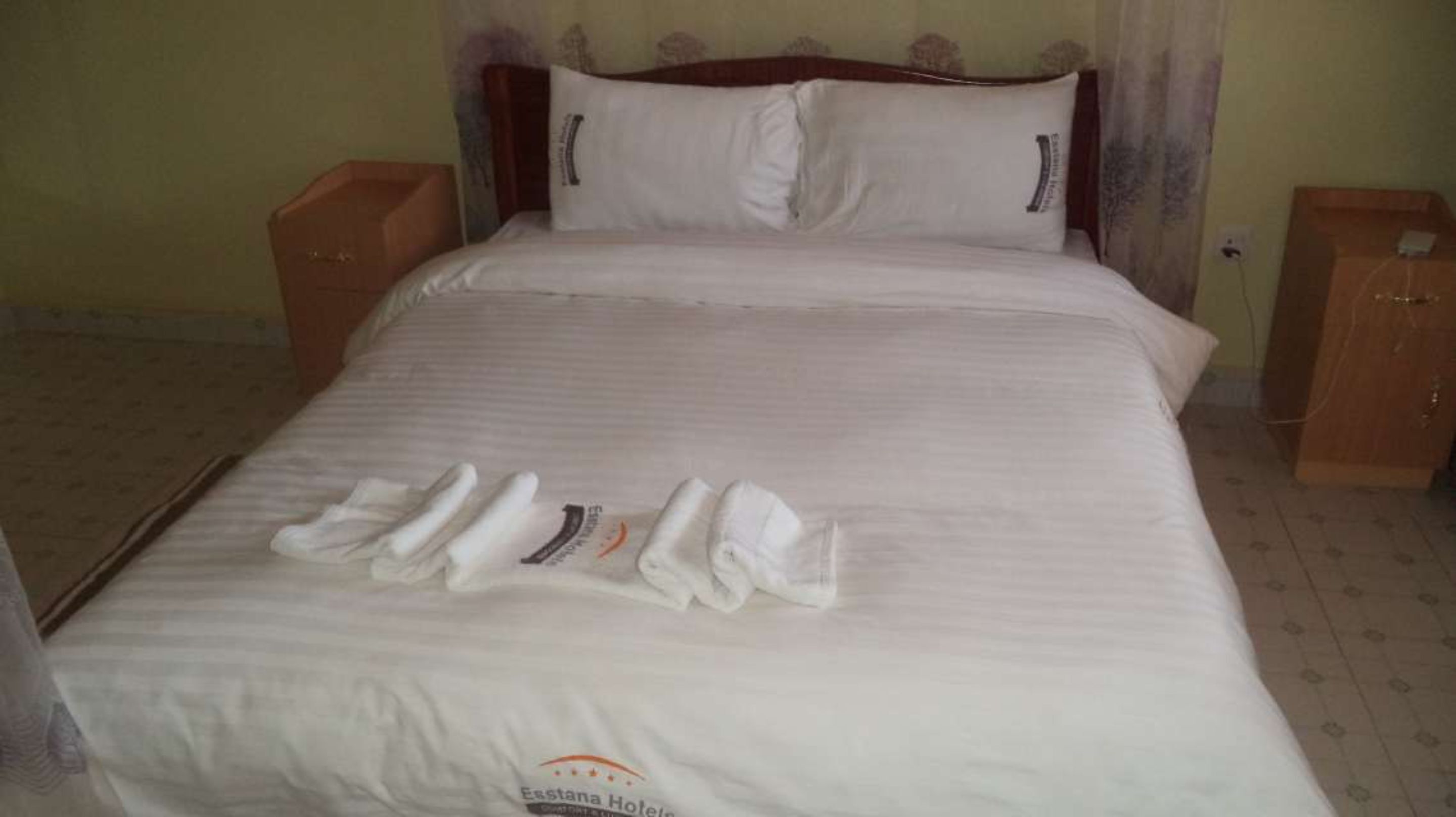 Una cama bien hecha con un almohadón y una toalla doblada.