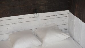 Una cama blanca con dos almohadas en una habitación con paredes de madera.