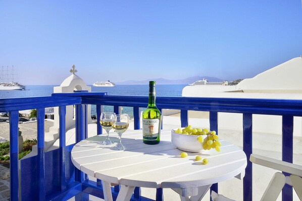 Ein Balkon mit Tisch für zwei Personen, einer Weinflasche und einer Zitronenschale.