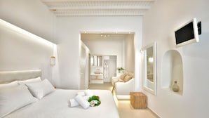 A modern hotel room with a large bed, a TV mounted on the wall, and a small wooden stool. - Marietta's Mykonos (Mykonos)