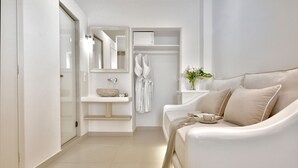 A modern bathroom with a glass shower, a white sink, and a beige sofa with a vase of flowers. - Marietta's Mykonos (Mykonos)