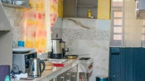 A modern kitchen with a marble backsplash, stainless steel appliances, and a blue trash bin. - Eldoret Luxurious Furnished Homes (Eldoret)
