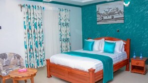 A bedroom with a wooden bed, a chair, a nightstand, and a painting on the wall. - Eldoret Luxurious Furnished Homes (Eldoret)