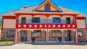 A two-story building with a red and beige facade, multiple balconies, and a tiled roof. - Eldoret Luxurious Furnished Homes (Eldoret)