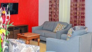 A living room with a grey sofa, a wooden coffee table, and a patterned armchair. - Eldoret Luxurious Furnished Homes (Eldoret)