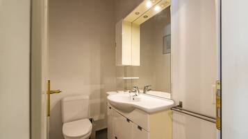Et lille, moderne badeværelse med toilet, vask og spejl.