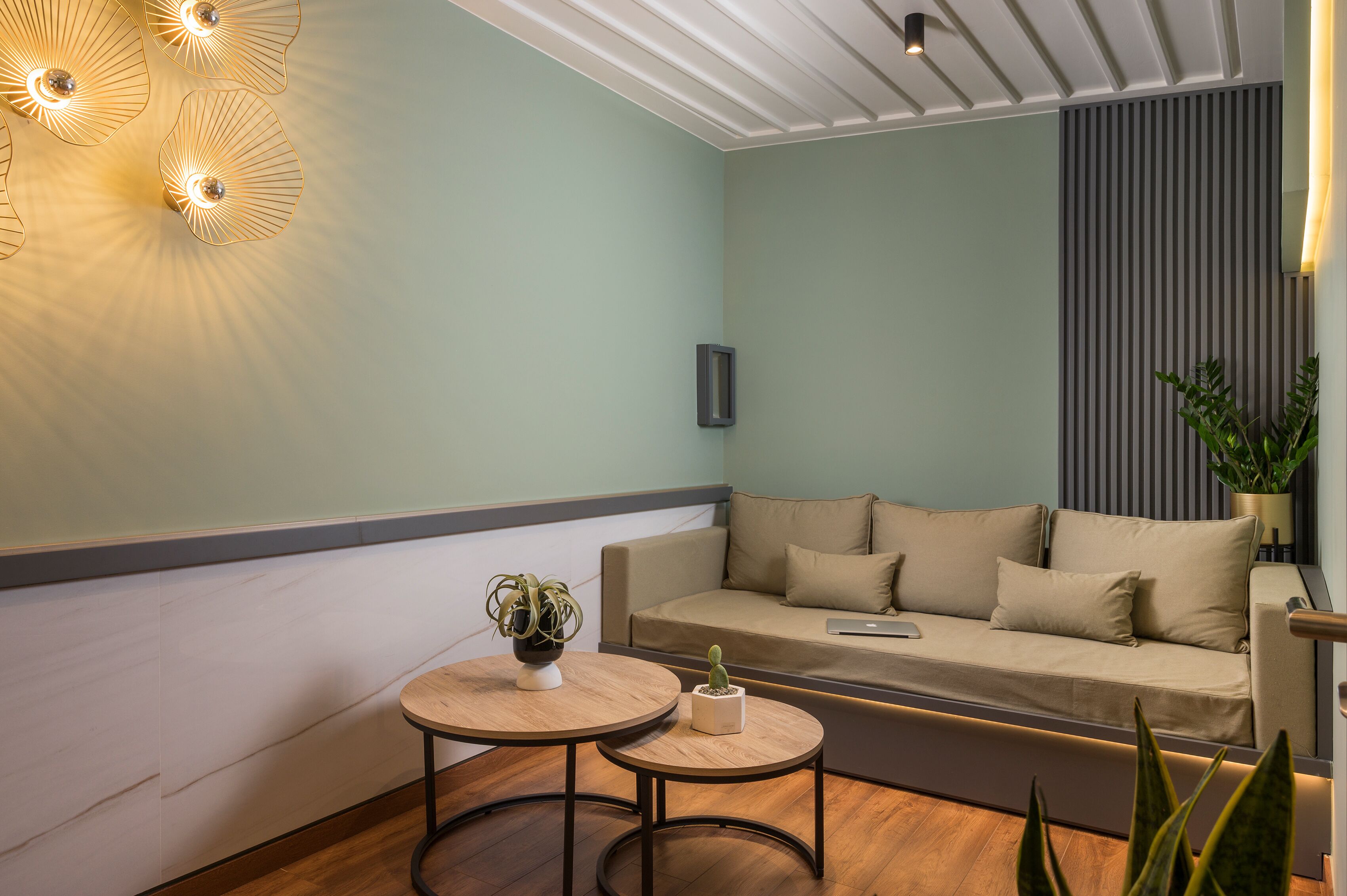 A modern living room with a sofa, two round tables, and decorative lighting.
