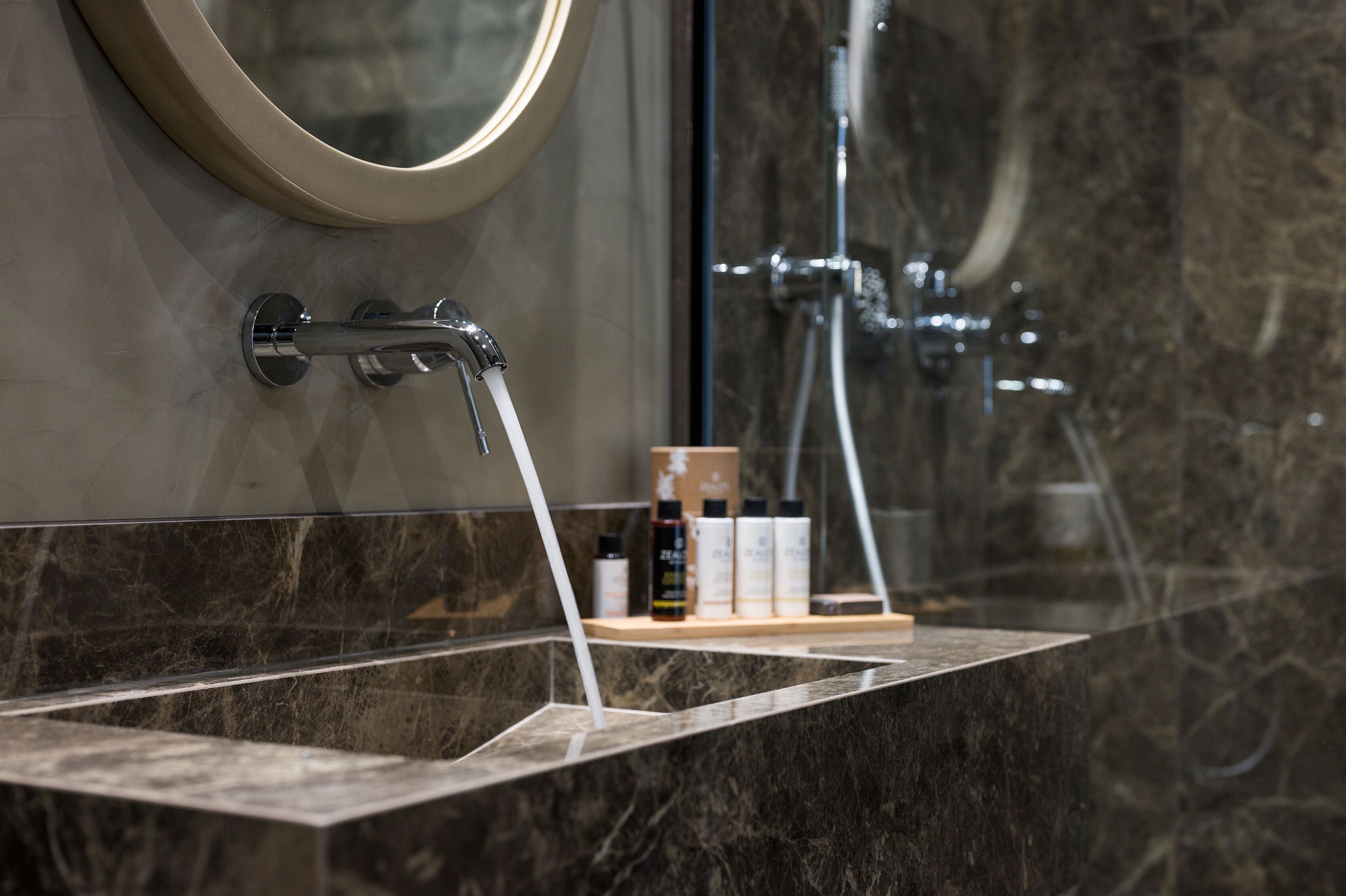 A bathroom with a marble sink, a mirror, and a shower area.