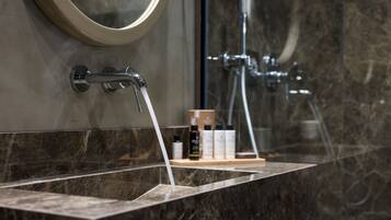 A bathroom with a marble sink, a mirror, and a shower area.