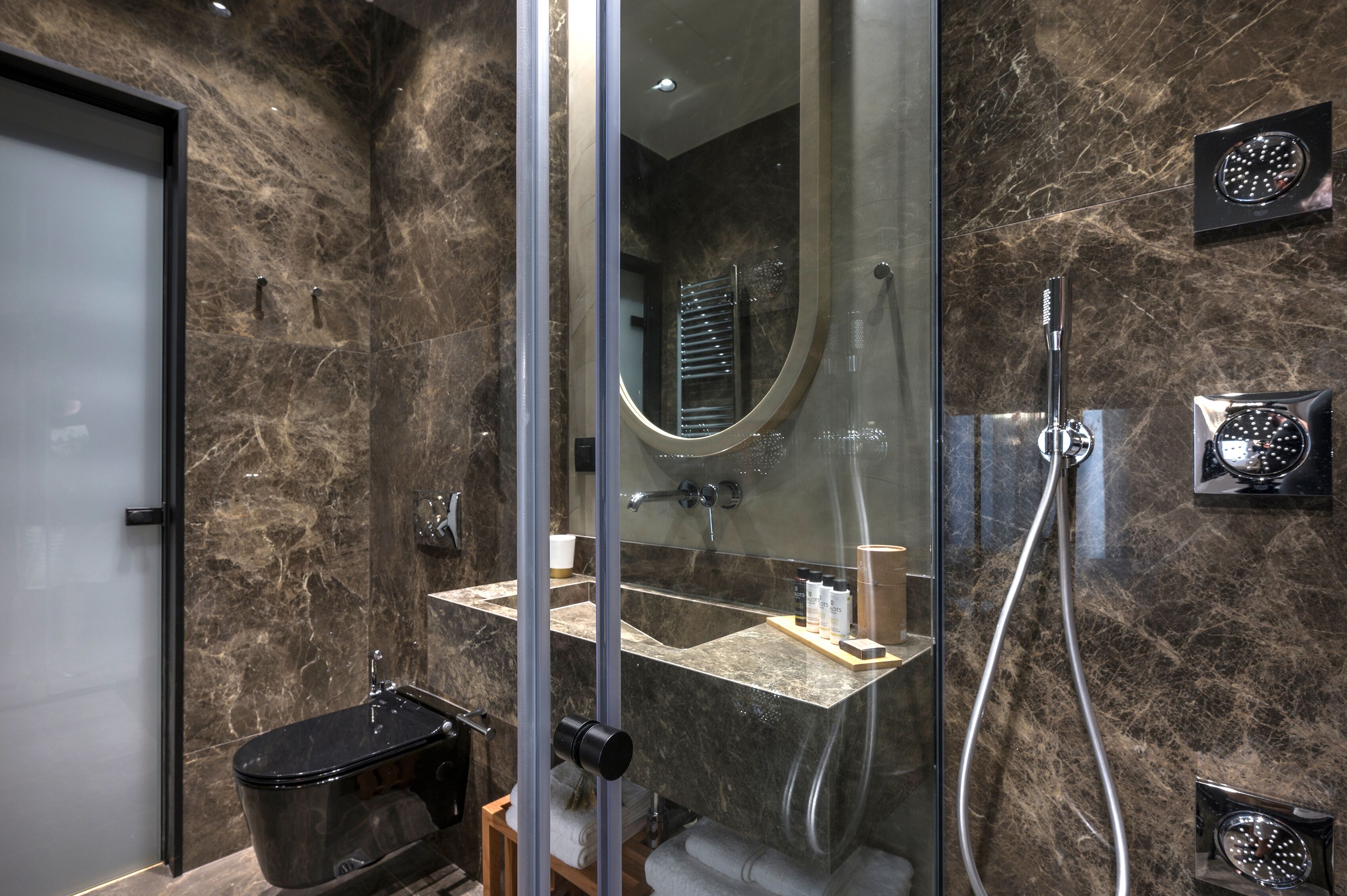 A modern bathroom with a glass-enclosed shower, a marble sink, and a toilet.