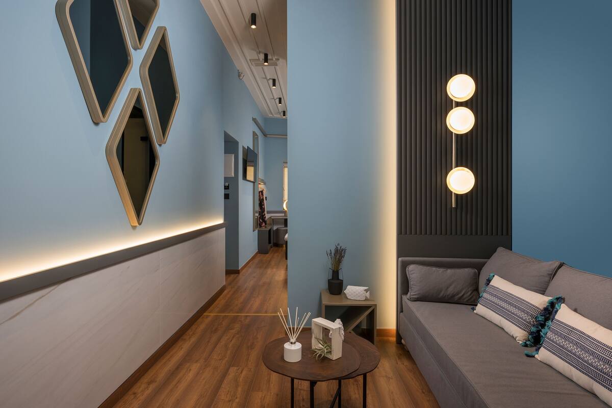Un moderno vestíbulo de hotel con piso de madera, un sofá con cojines estampados y una mesa redonda con un jarrón decorativo.