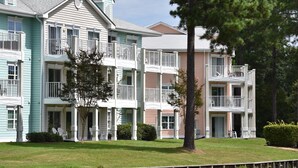 A multi-story building with balconies and a well-maintained lawn.