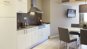 Een moderne keuken met witte kastjes, een roestvrijstalen afzuigkap en een eethoek met een tafel en stoelen.