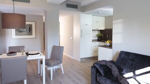 Ein modernes Wohnzimmer mit Essbereich, einem grauen Sofa und einer Küche im Hintergrund.