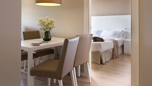 Ein modernes Hotelzimmer mit Essbereich, einem Bett mit weißer Bettwäsche und einer Pendelleuchte.