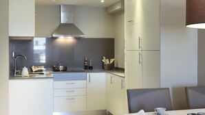 Une cuisine moderne avec des meubles blancs, des appareils en acier inoxydable et un coin repas comprenant une table et des chaises.