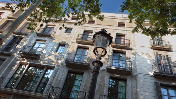 Un immeuble à plusieurs étages, doté de balcons, de grandes fenêtres et d’un lampadaire.