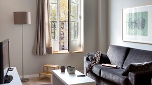 Un salon moderne avec un canapé gris, une table basse blanche, un lampadaire et une fenêtre avec des rideaux.