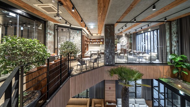 Un vestíbulo amplio con una escalera, vigas de madera y ventanas grandes.