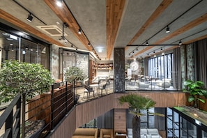 Un vestíbulo amplio con una escalera, vigas de madera y ventanas grandes.