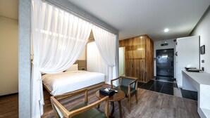 Una habitación de hotel con una cama, dos sillas, una mesita y un escritorio.
