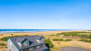 A two-story house with a dark roof and green trim, located near a beach with dunes and sparse vegetation. - OCEAN FRONT, Pets OK, Ping Pong, Near Town and Discovery Trail (Ocean View B) (Long Beach)