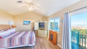 A bedroom with a bed, a ceiling fan, a TV, a fireplace, and a large window with a view. - OCEAN FRONT, Pets OK, Ping Pong, Near Town and Discovery Trail (Ocean View A) (Long Beach)