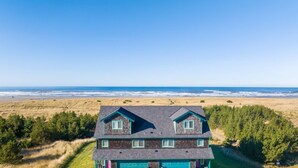 A two-story house with a dark roof and light-colored walls, located near a beach with a clear view of the ocean. - OCEAN FRONT, Pets OK, Ping Pong, Near Town and Discovery Trail (Ocean View A) (Long Beach)
